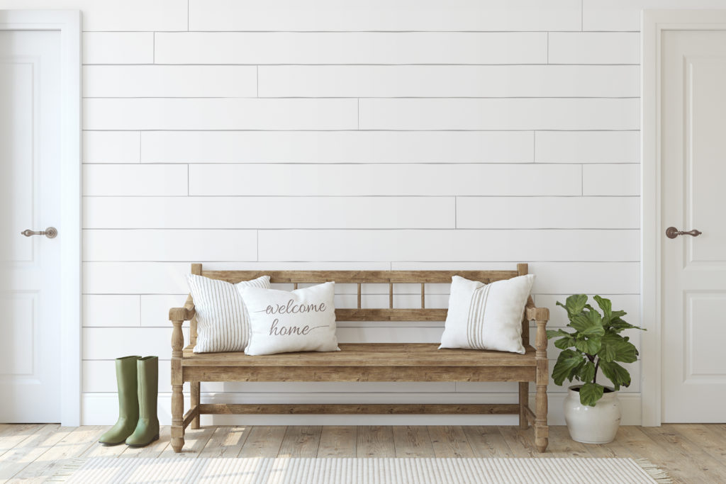 Modern farmhouse entryway with rustic bench white throw pillows and white planter against ship lap walls. 